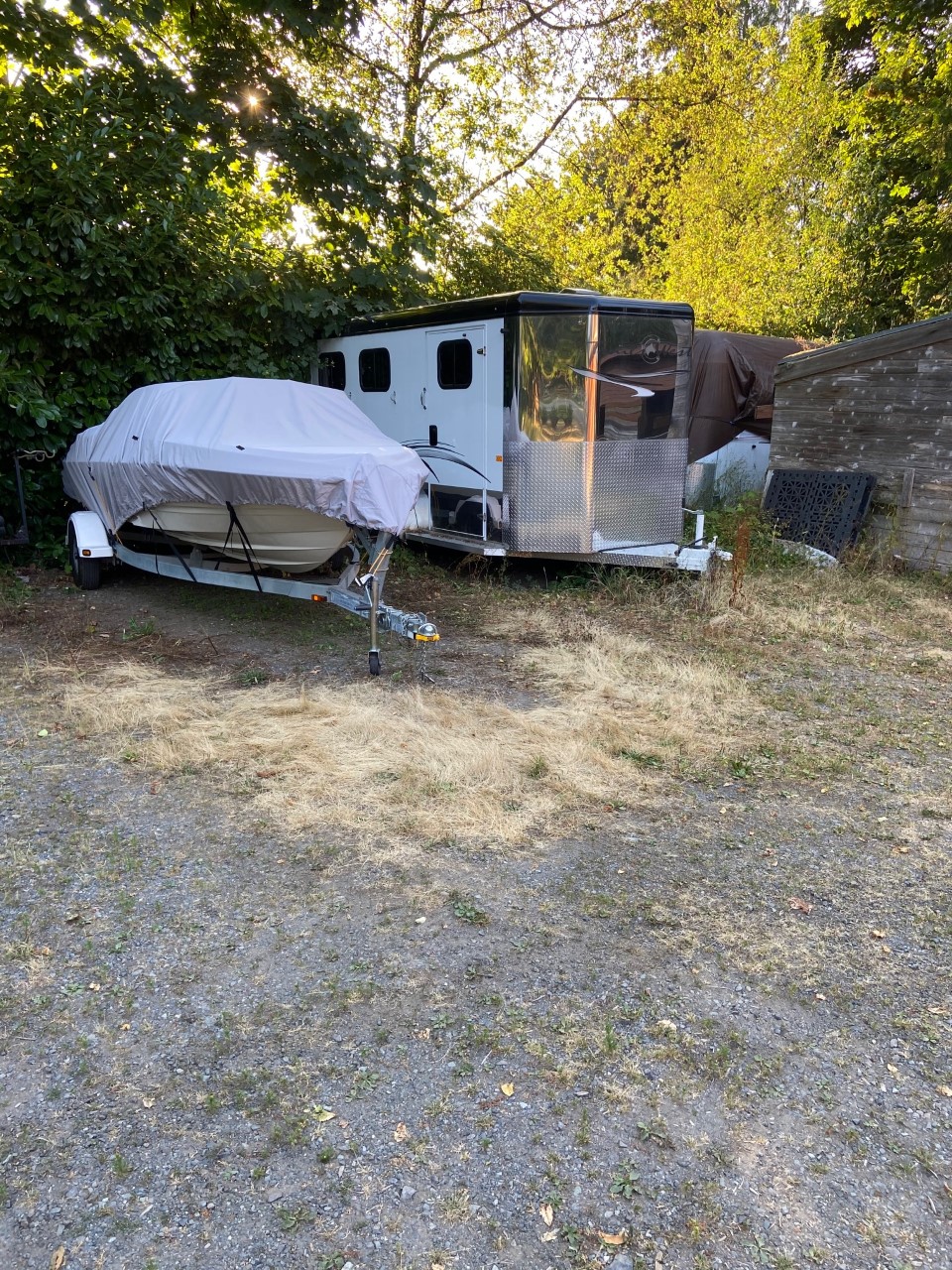 a trailer parked in the barn lot beside a boat